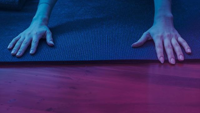 Female hands on yoga mat in ambient lighting reflecting relaxation