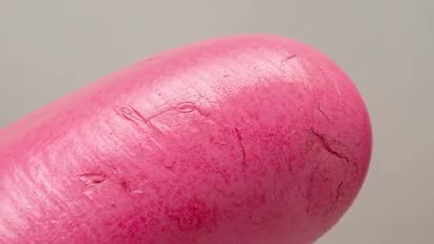 Macro video revealing painted fingertip cracking pink pigment and intricate skin texture
