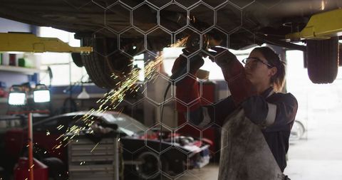 Caucasian woman performing car maintenance in workshop
