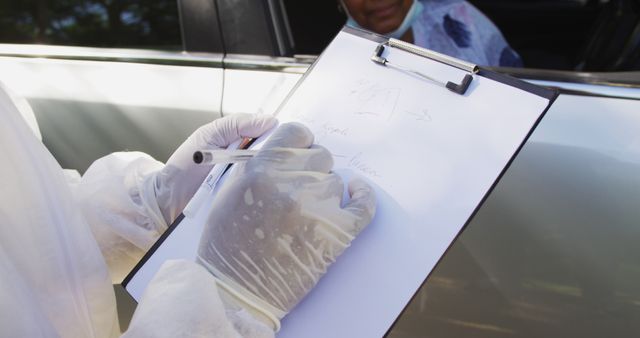 Mid section of health worker in protective clothes taking notes on clipboard on the road. testing for prevention of coronavirus outbreak concept