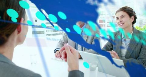 Smiling businesswoman leading collaborative boardroom meeting with laptop and documents