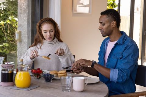 Diverse couple enjoying cozy brunch with pancakes and coffee at home