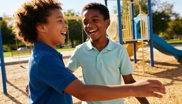 Playground laughter two boys hugging and laughing by blue slide yellow railings sunny park