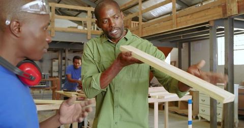 African American Woodworkers Collaborating on Project in Workshop