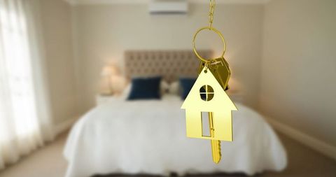 Golden house keychain with keys in luxurious bedroom setting