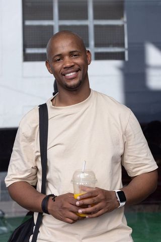 Smiling african american man holding cold drink wearing casual tee shoulder bag smartwatch
