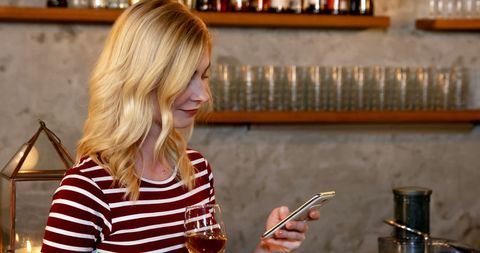 Woman in Striped Shirt Texting at Bar with Drink - Download Free Stock Images Pikwizard.com