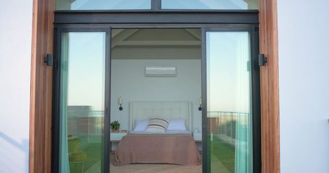 Sliding glass doors framing coastal bedroom with tufted headboard and balcony view
