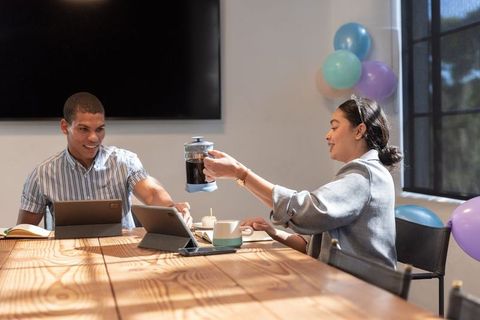 Colleagues Sharing Coffee in Modern Office During Team Meeting