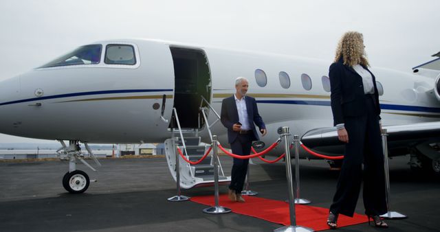 Business professionals are exiting a private jet, stepping onto a red carpet, symbolizing luxury and success. Great for illustrating business travel, executive lifestyle, corporate events, and high-end travel experiences. Suitable for use in travel brochures, corporate materials, and business-oriented websites.