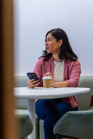 Young woman relaxing with coffee and smartphone in modern minimalist cafe lounge