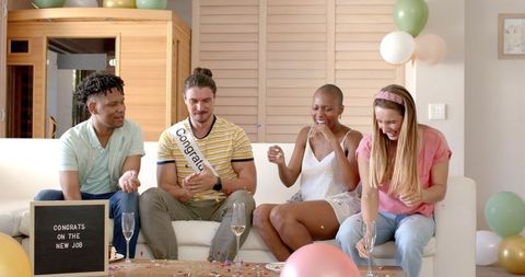 Friends celebrating new job with confetti at home party