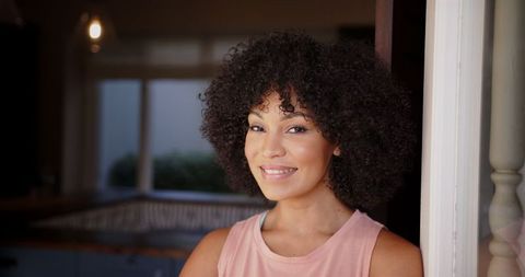 Smiling Woman with Curly Hair Relaxed at Home Indoors