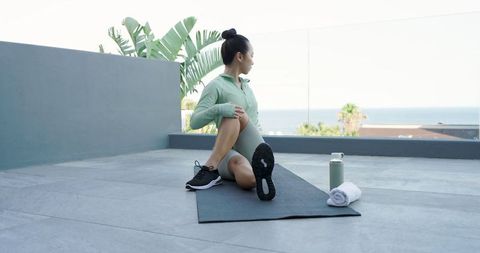 Woman Practicing Yoga Twists on Rooftop With Scenic Ocean View