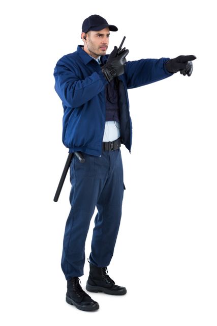 Security officer in uniform using a walkie-talkie and pointing with right hand. Ideal for use in articles related to law enforcement, security services, public safety, crime prevention, and communication in security operations.