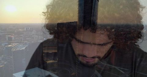 Contemplative bearded man overlooking modern skyline at dusk