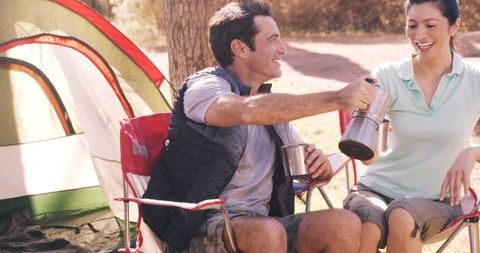 Happy Couple Enjoying Coffee While Camping Outdoors