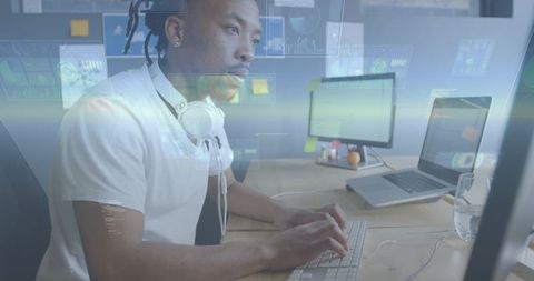 Black software developer typing at workstation with dual screens, coding and focusing