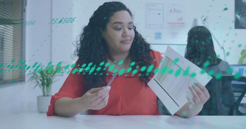 Biracial businesswoman analyzing reports with digital overlay