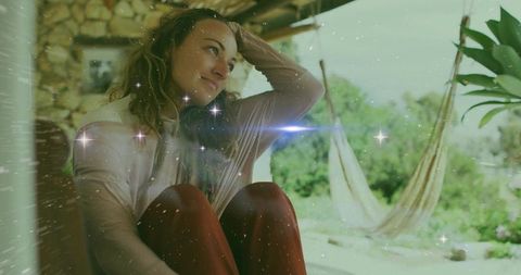 Contemplative woman relaxing on porch with hammocks and garden view