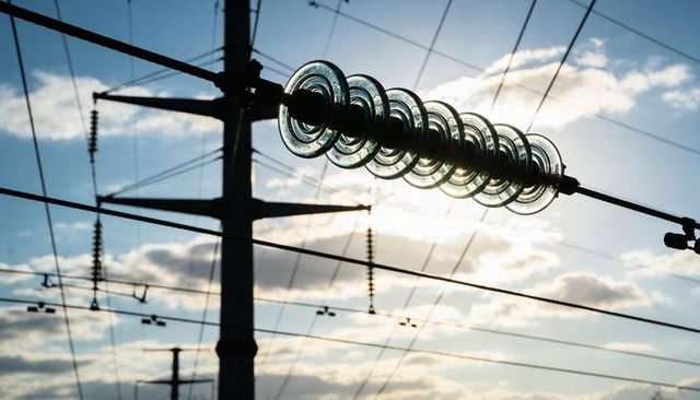 Backlit glass disc insulator string refracting sunlight on high-voltage transmission line