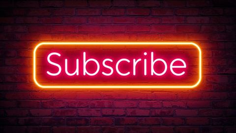 Neon subscribe button glowing pink-orange on red brick wall with dramatic glow