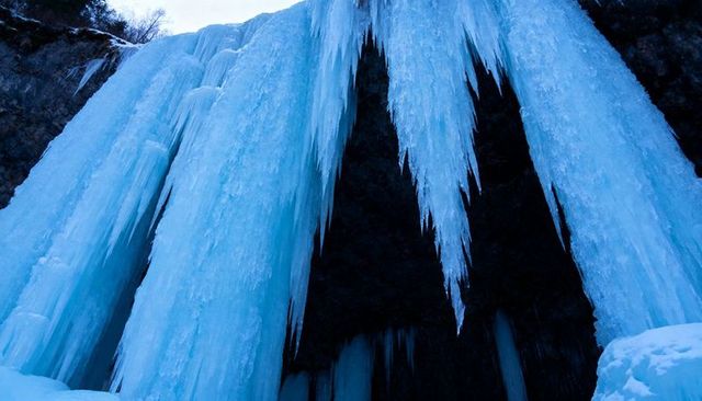 Frozen icicle cave: towering blue ice columns and pointed stalactite formations