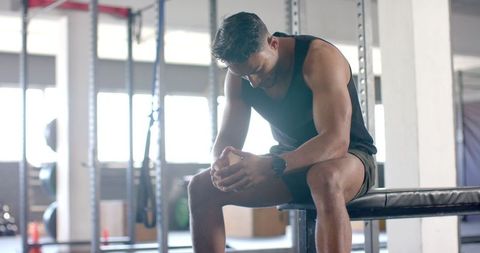 Muscular Man Resting on Bench in Gym for Fitness and Strength