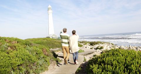 Senior Couple Enjoys Stroll Along Coastal Path to Lighthouse - Download Free Stock Images Pikwizard.com