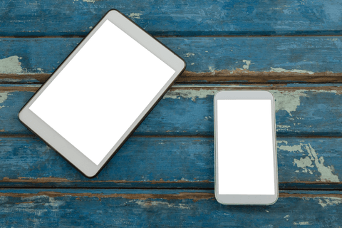 Transparent mobile phone and tablet on distressed wooden surface