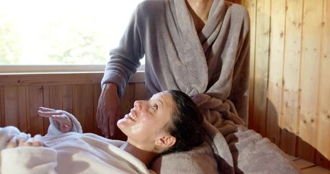 Couple reclining in plush robes relaxing on wood-paneled spa bench enjoying wellness glow