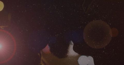 Couple gazing under starry sky, cinematic lens flare and bokeh silhouettes, romantic mood