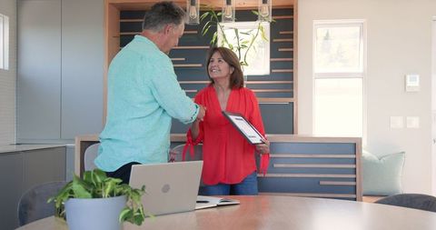 Senior Couple Smiling While Shaking Hands with Tablet at Home Office