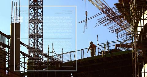 Backlit Construction Worker Walking on Scaffold with Tower Crane and Urban Silhouette