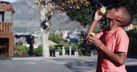 Boy blowing bubbles in school playground having fun outdoors