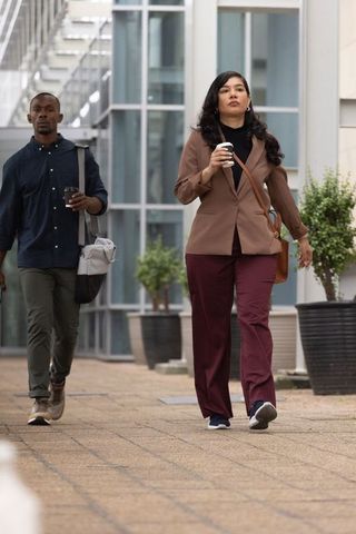 Diverse urban commuters walking holding takeaway coffee outside glass office building