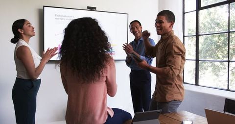 Diverse team engaged in lively discussion and applause at meeting