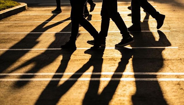 Walking shadows crossing parking lines at golden hour urban pedestrians feet silhouettes
