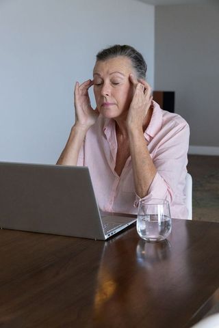 Senior Woman Practicing Mindfulness at Home with Laptop and Water