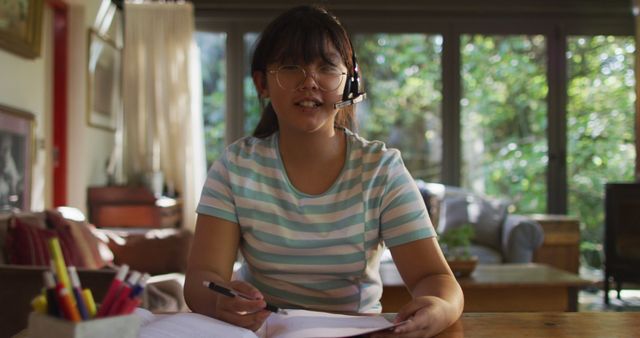 Smiling Asian Girl with Headset Doing Homework at Home - Download Free Stock Images Pikwizard.com