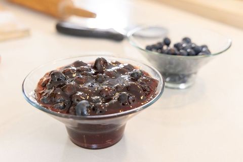Glossy blueberry compote in glass bowl on kitchen counter, homemade jam closeup