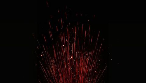 Vertical red spark fountain rising with long exposure light trails on black background