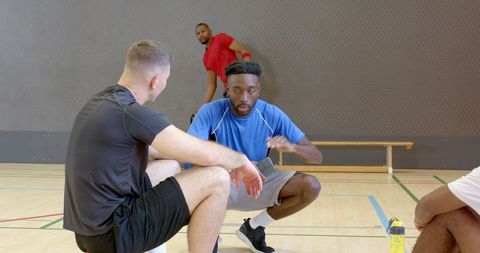 Multiracial team fist bumping, discussing strategy and rehydrating during gym break