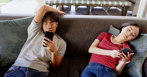 Modern Couple Relaxing with Smartphones in Outdoor Living Space