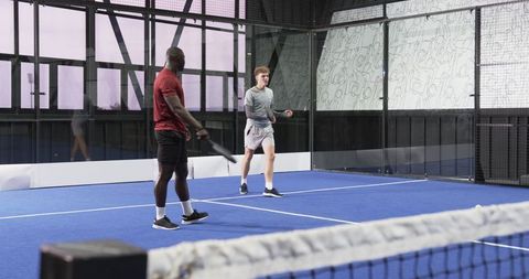 Dynamic Padel Players Competing on Blue Court