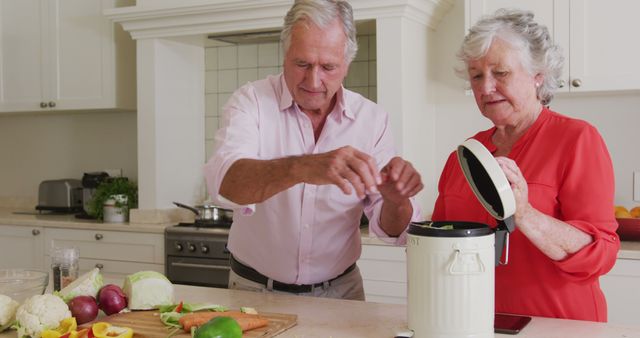 Senior couple composting vegetable scraps in modern kitchen. Highlighting the importance of sustainable living and environmentally friendly practices. Ideal for use in marketing for eco-friendly kitchen products, composting guides, or campaigns promoting sustainability and waste reduction.