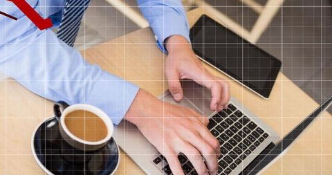Businessman typing on laptop with coffee and tablet, red arrow and grid overlay