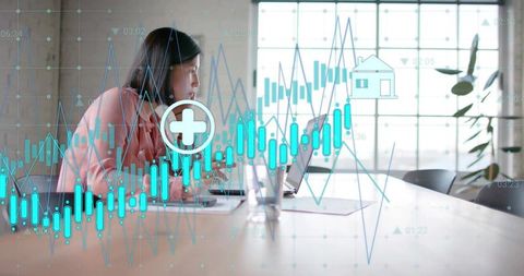 Korean businesswoman analyzing financial charts on laptop with blue analytics overlay