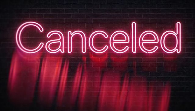 Neon canceled sign glowing pink on dark brick wall with magenta light streaks and haze