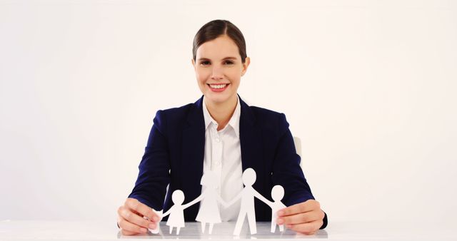 Businesswoman holding paper family cutouts symbolizing care and support. Ideal for content related to insurance, family support services, and work-life balance. Useful for illustrating themes of togetherness and professional care.